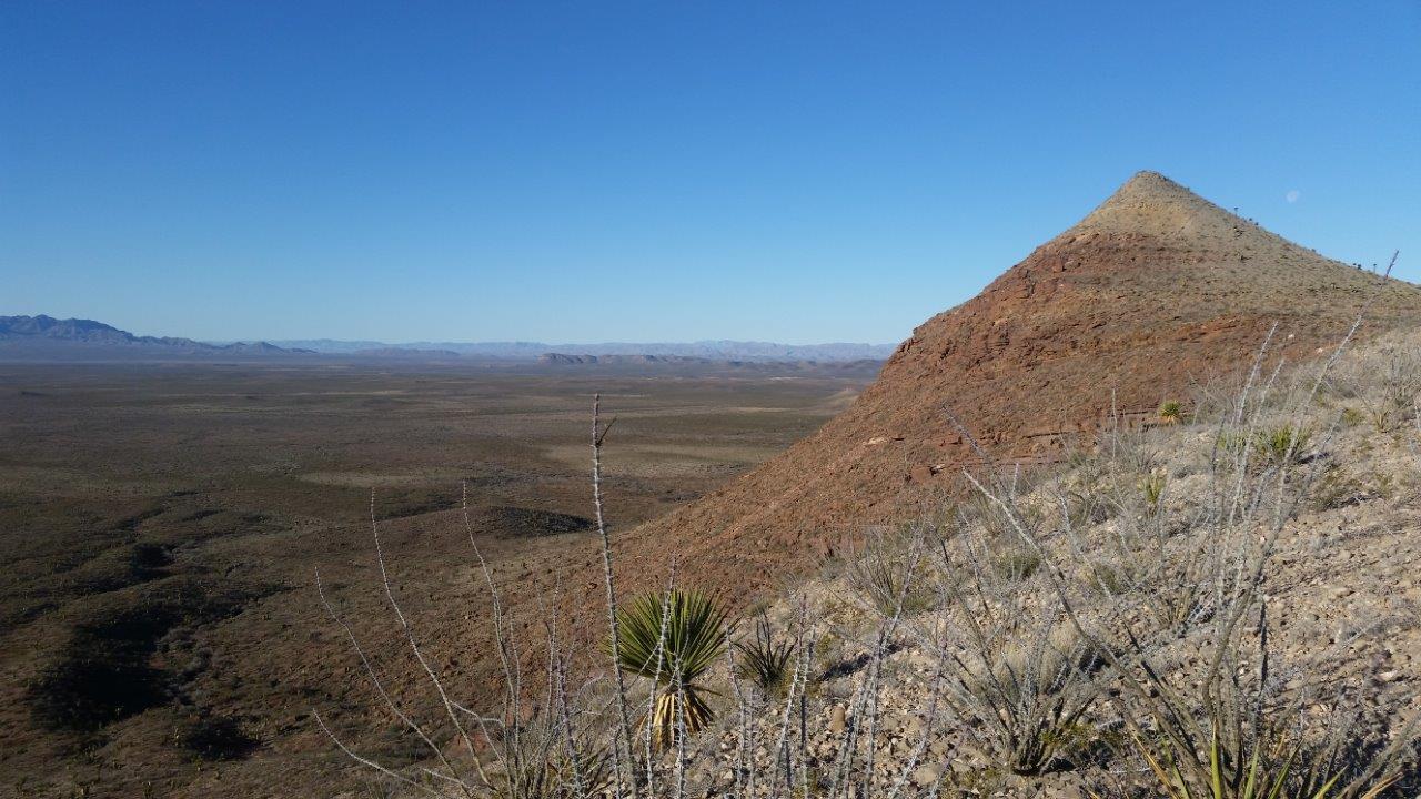 A lone pointed desert peak rising from scrub and grassland beside I-10 in Far West Texas