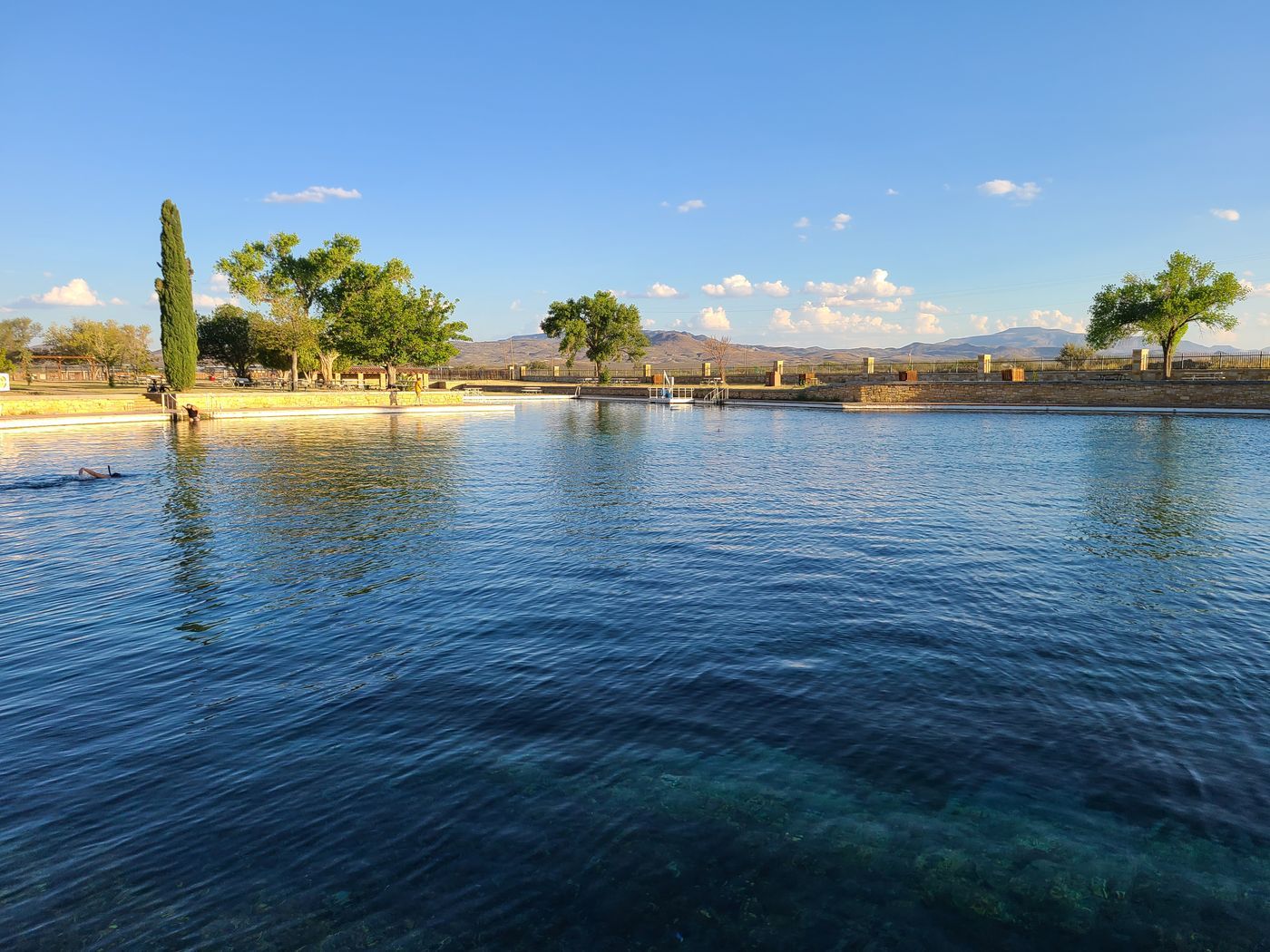 The wide clear expanse of the San Solomon Springs pool at Balmorhea State Park in the evening, with low hills beyond