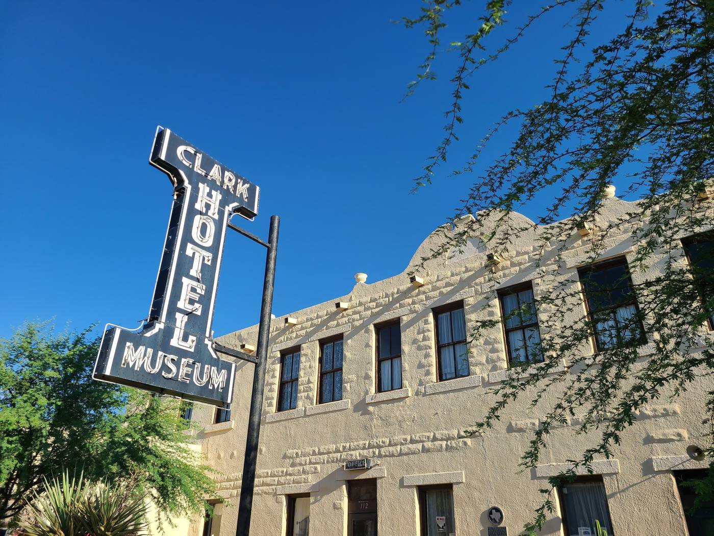 The tall vertical neon Clark Hotel Museum sign on the historic stone hotel building in Van Horn, Texas