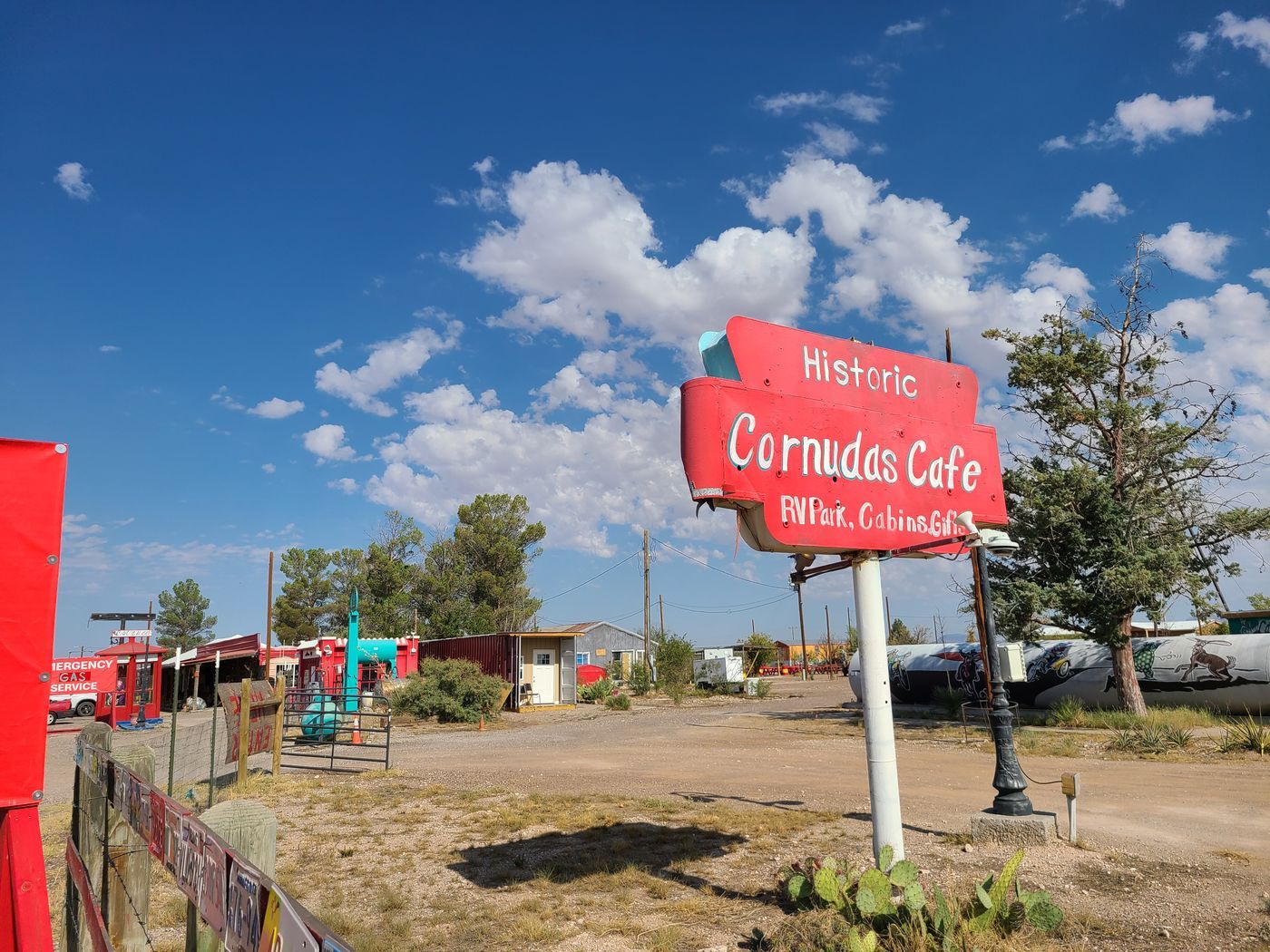 Hand-painted red roadside sign for the Historic Cornudas Cafe, advertising an RV park, cabins and gifts, under a blue West Texas sky