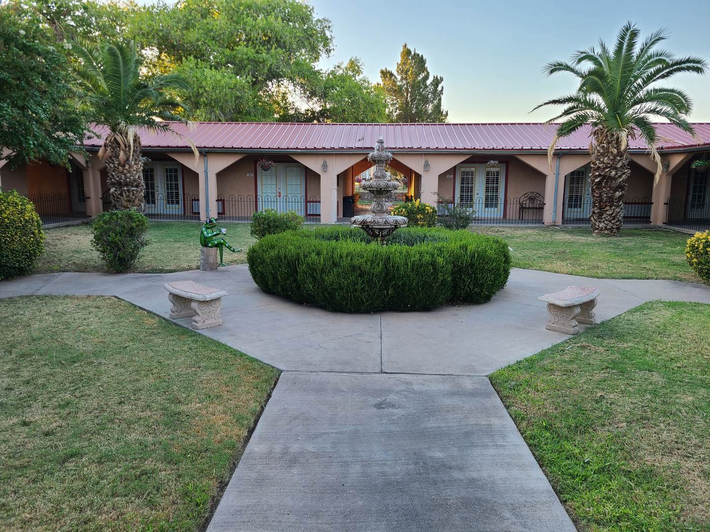 The central courtyard at El Oso Flojo Lodge in Balmorhea, with a walkway, lawn and stone benches