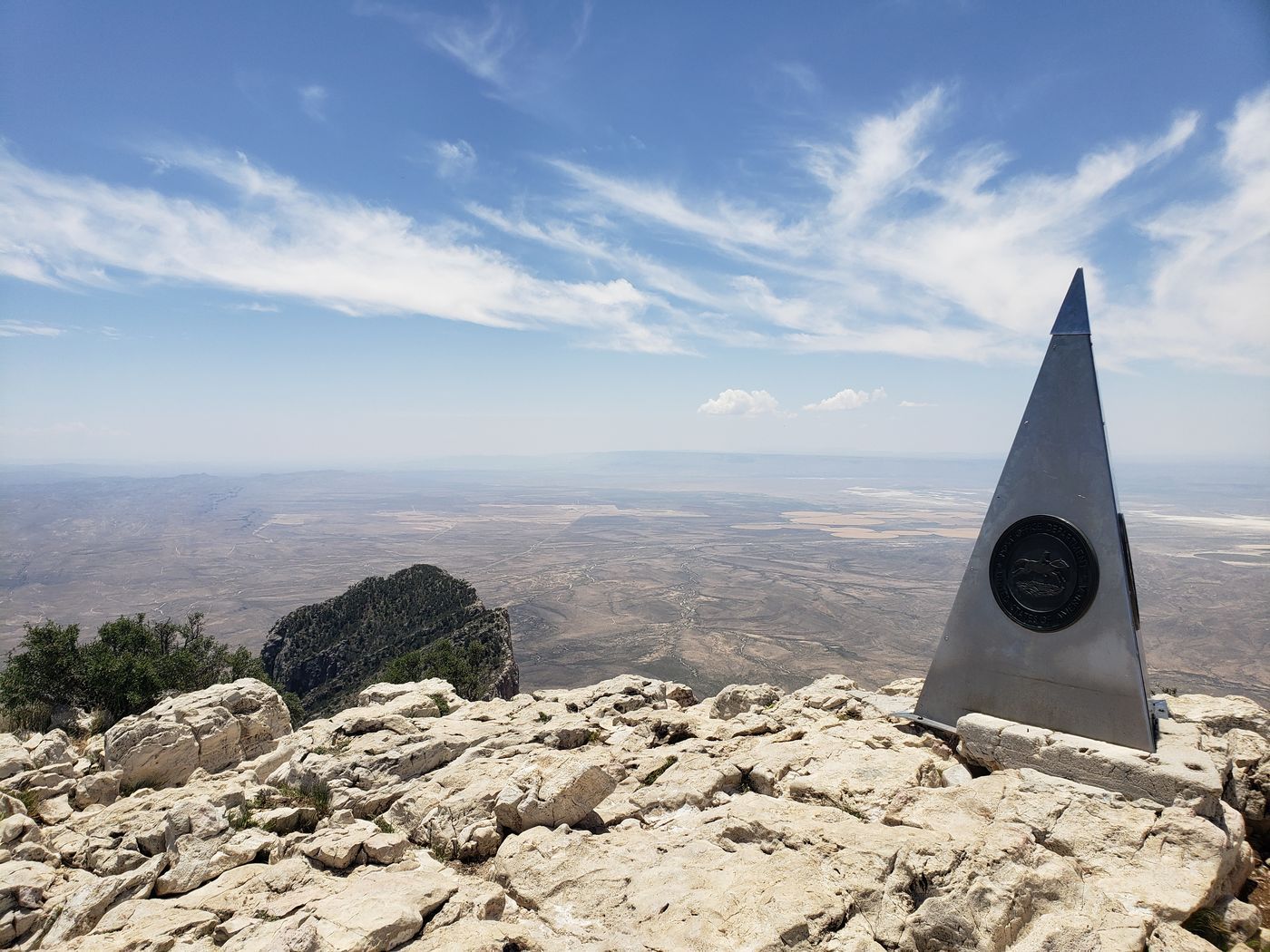 The metal pyramid monument marking the summit of Guadalupe Peak, the highest point in Texas, with the desert plain far below