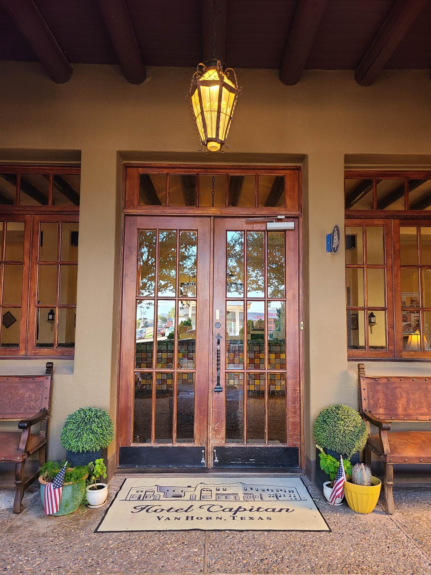 The arched entrance of the Hotel El Capitan in Van Horn, Texas, with a hanging lantern and potted plants either side