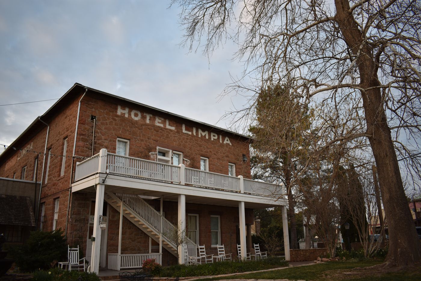 The Hotel Limpia in Fort Davis, Texas, with rocking chairs along its two-story porch under bare trees