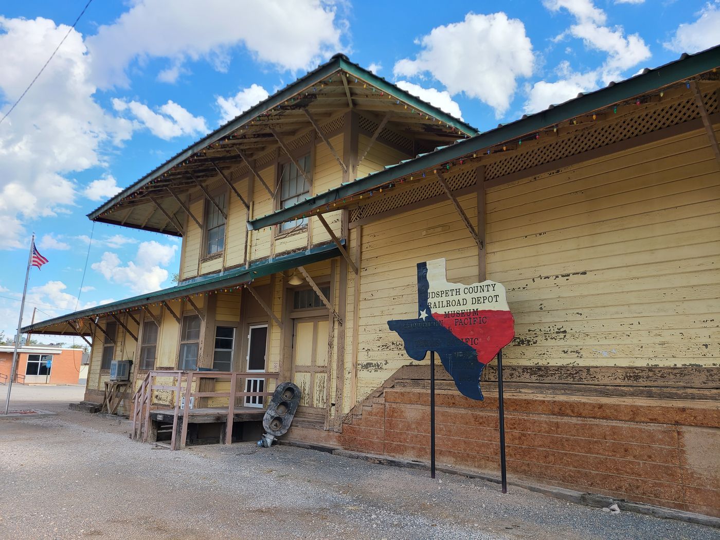 The restored wooden railroad depot at Sierra Blanca, Texas, with wide eaves and a Texas flag on the platform